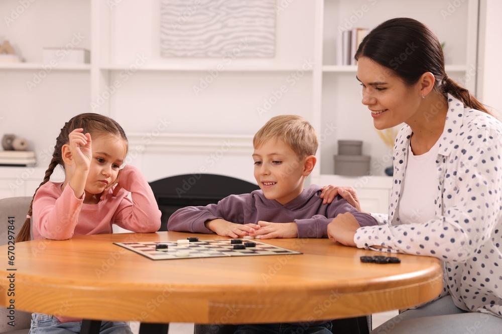 Family playing checkers at wooden table in room Family playing checkers at wooden table in room