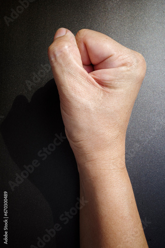 Woman's hand with fist gesture, Right side, on black background, Asian body skin part, Symbol, Gesturing, Body Language Concept photo