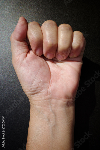 Woman's hand with fist gesture, Front left side, on black background, Asian body skin part, Symbol, Gesturing, Body Language Concept photo