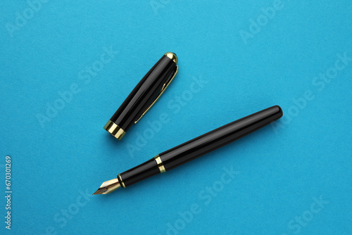 Stylish fountain pen with cap on light blue background, flat lay
