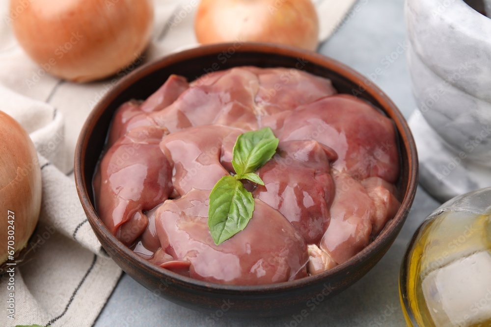 Bowl with raw chicken liver and basil on light grey table, closeup Bowl with raw chicken liver and basil on light grey table, closeup