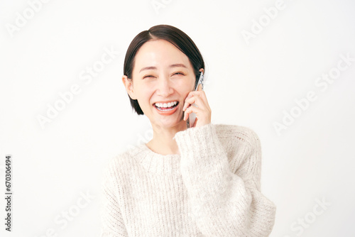 スマートフォンで電話する女性 白背景 カメラ目線