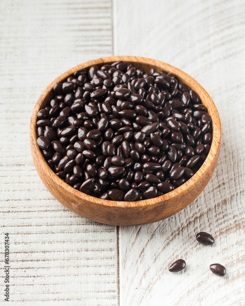 Sunflower seeds in chocolate in a wooden plate on a white background. Sunflower seeds in chocolate in a wooden plate on a white background.