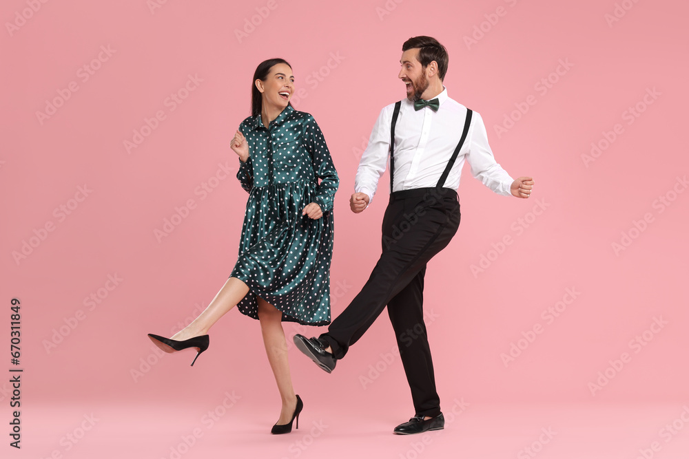Happy couple dancing together on pink background Happy couple dancing together on pink background