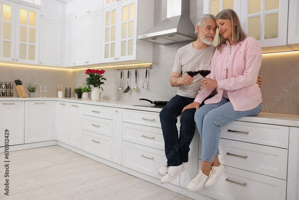 Happy affectionate senior couple with glasses of wine in kitchen. Space for text Happy affectionate senior couple with glasses of wine in kitchen. Space for text