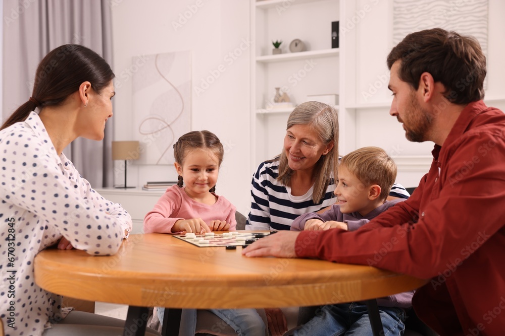 Family playing checkers at wooden table in room Family playing checkers at wooden table in room