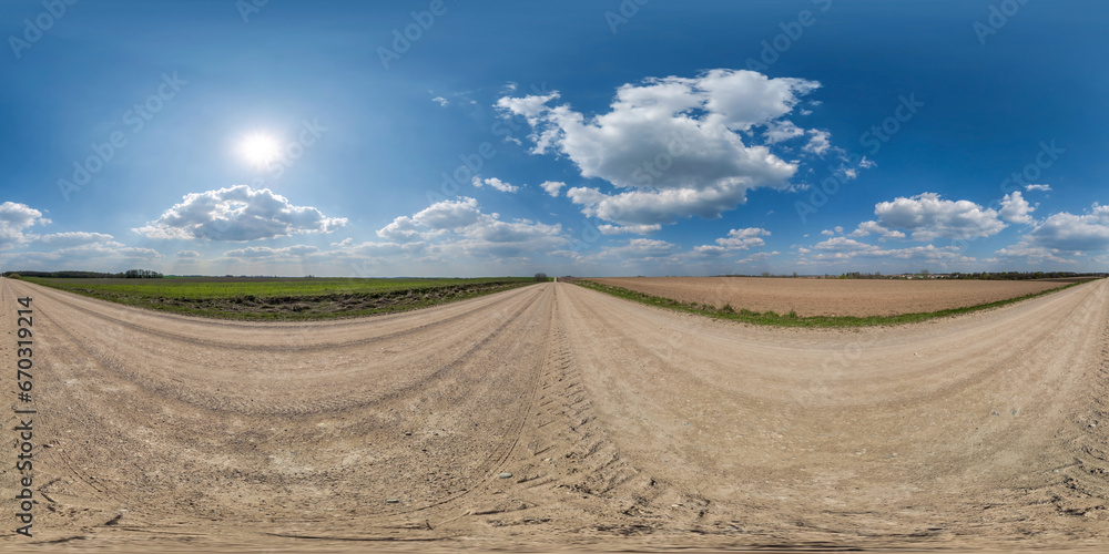 Fototapeta premium 360 hdri panorama on gravel road with marks from car or tractor tires with clouds on blue sky in equirectangular spherical seamless projection, skydome replacement in drone panoramas