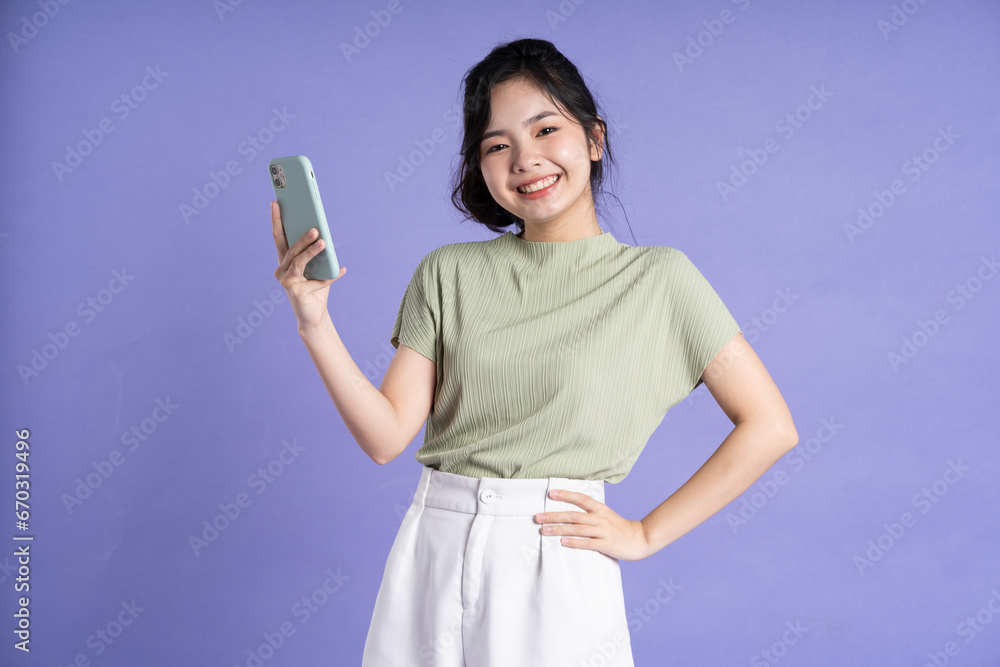 Portrait of beautiful asian woman using smartphone on purple background Portrait of beautiful asian woman using smartphone on purple background
