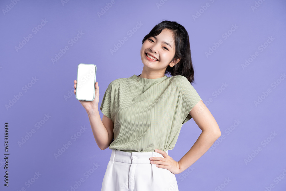Portrait of beautiful asian woman using smartphone on purple background Portrait of beautiful asian woman using smartphone on purple background