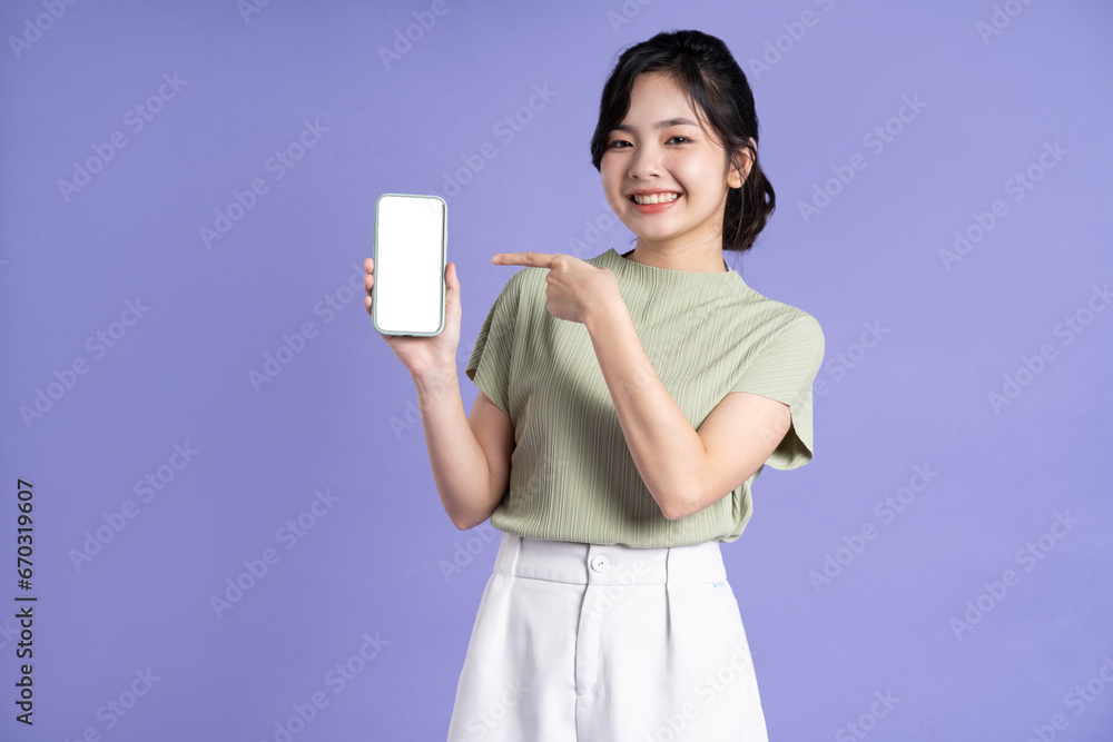 Portrait of beautiful asian woman using smartphone on purple background Portrait of beautiful asian woman using smartphone on purple background