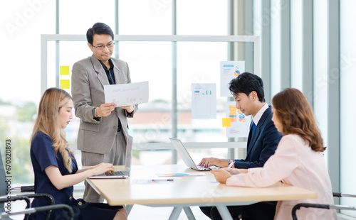 Asian professional successful male and female businessman businesswoman partnership colleagues in formal business suit sitting standing listening to presenter in meeting room in company office