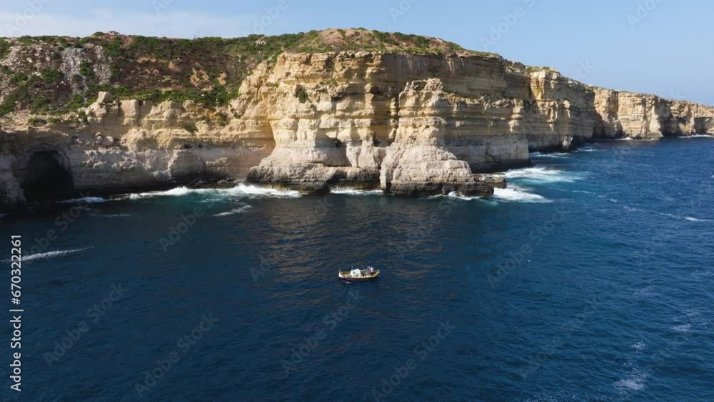 Aerial view around a boat on the steep, rocky coastline of the sunny Malta island Aerial view around a boat on the steep, rocky coastline of the sunny Malta island