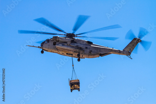 Sikorsky CH-53 Sea Stallion Military helicopter in formation and carrying cargo humvee