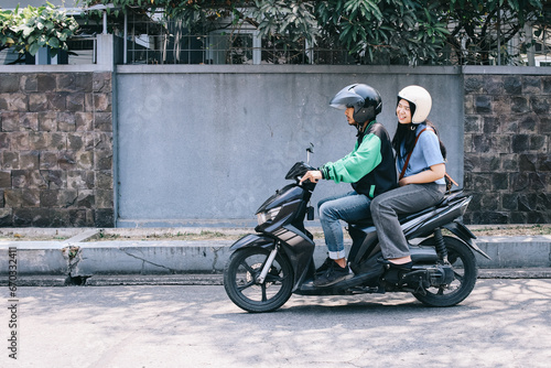 Online motorcycle taxi driver in helmet with female passenger going to destination