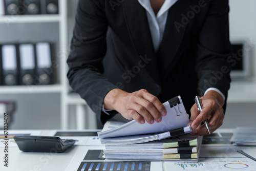 Asian businesswoman searches through piles of financial documents to make calculations Marketing analysis Tax administration Statistical accounting report on the desk in the office office.