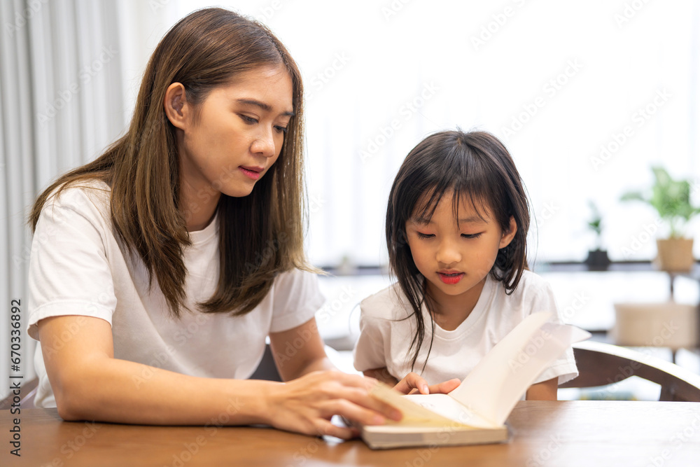 Portrait happy love asian family mother teach little daughter asian girl learn and study on table.Mom and asian young girl read book making lessons in homeschool at home.Education Portrait happy love asian family mother teach little daughter asian girl learn and study on table.Mom and asian young girl read book making lessons in homeschool at home.Education