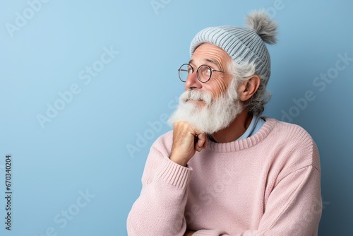 Portrait of an elderly man with a large gray beard and lush hair with a thoughtful look to the side. Blue background. Generated by AI.