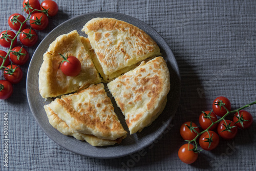 Homemade cheese filled savoury pies khachapury on grey plate served with tomatoes. Selective focus