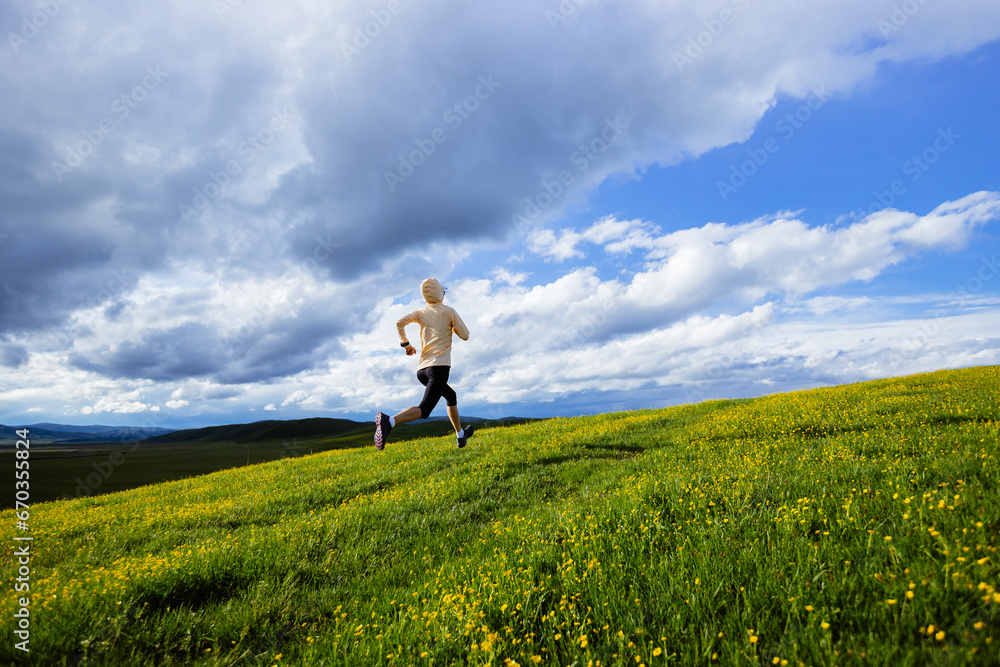 Woman trail runner cross country running at high altitude flowering mountain Woman trail runner cross country running at high altitude flowering mountain