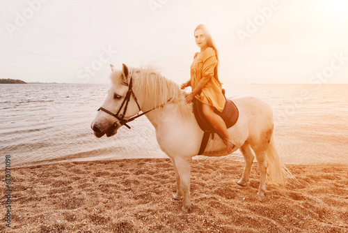 A woman in a dress stands next to a white horse on a beach, with the blue sky and sea in the background. © svetograph