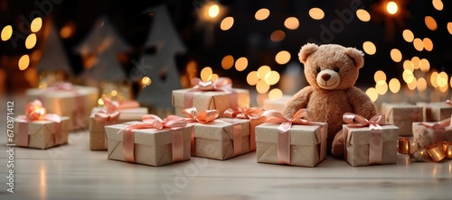 In a wide-format Christmas-themed background image, a teddy bear is encircled by presents adorned with pink ribbons, providing room for customization. Photorealistic illustration