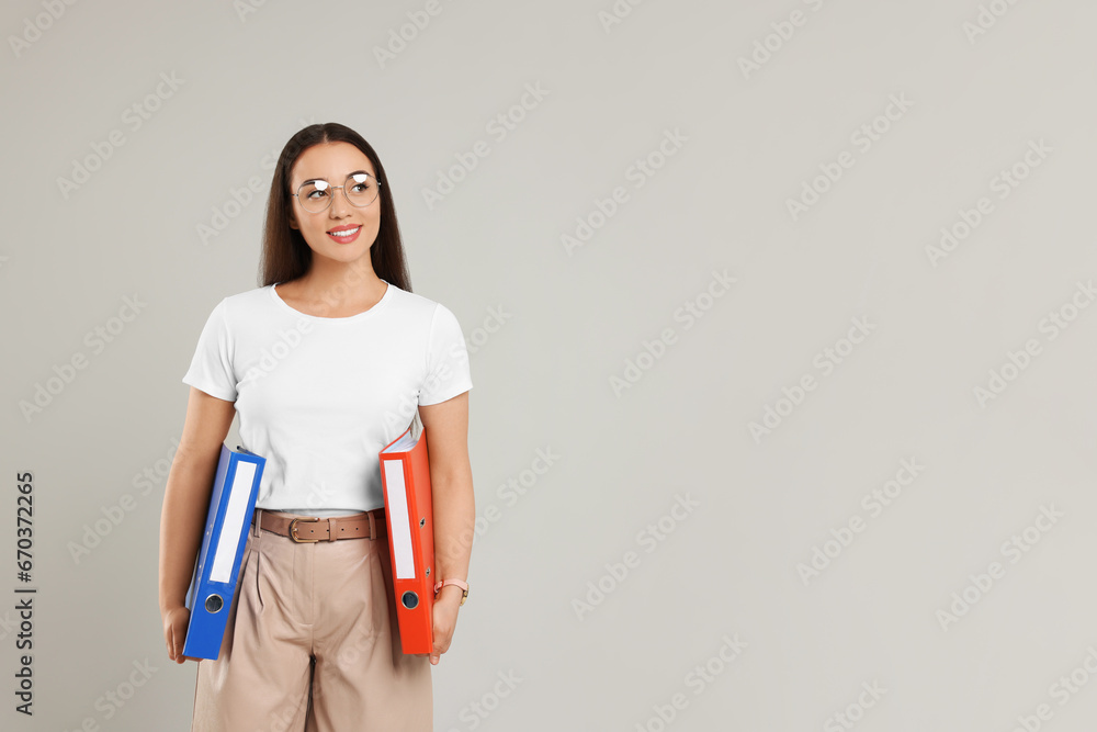 Happy woman with folders on light gray background, space for text Happy woman with folders on light gray background, space for text