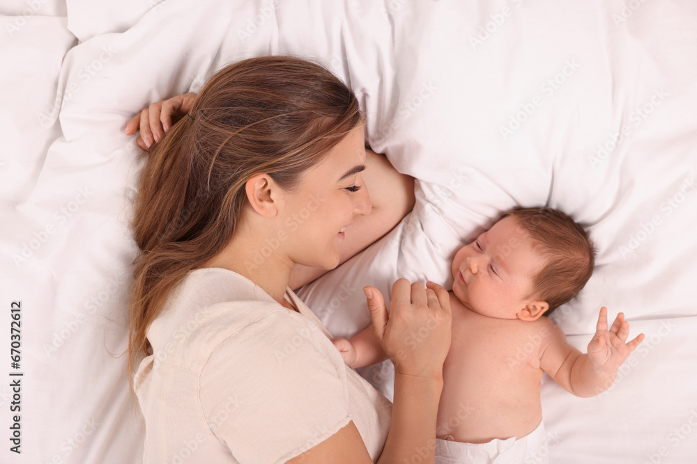 Mother and her cute newborn baby on bed, top view Mother and her cute newborn baby on bed, top view