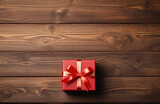 Christmas gift box with red ribbon and fir tree branch on wooden background