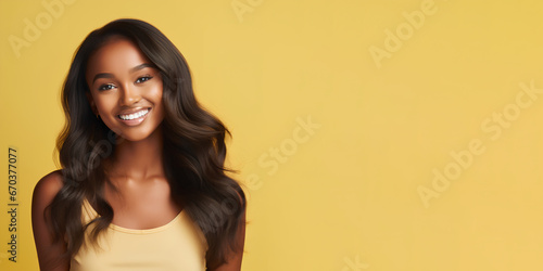 Smimilg young woman with dark skin and long groomed hair isolated on flat yellow pastel background with copy space. Model for banner of cosmetic products, beauty salon and dentistry © SappiStudio