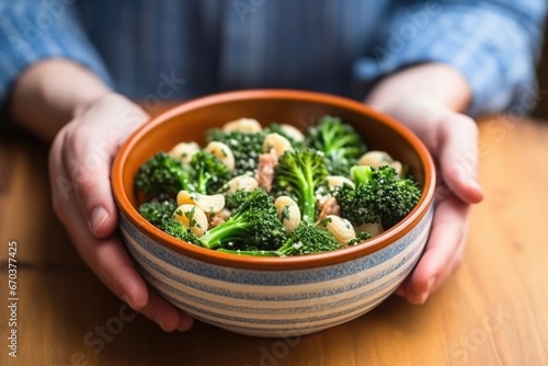 hand holding a bowl of orecchiette with broccoli rabe photo