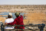 Rear view of young couple observing animals in African savannah, Etosha National Park, Namibia