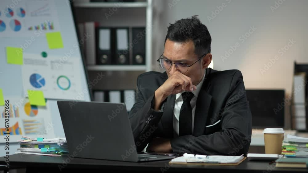 Asian businessman suffering from stress, eyestrain, headache searching for financial information, stats, graphs, income charts. while working online on laptop computer at office. Asian businessman suffering from stress, eyestrain, headache searching for financial information, stats, graphs, income charts. while working online on laptop computer at office.