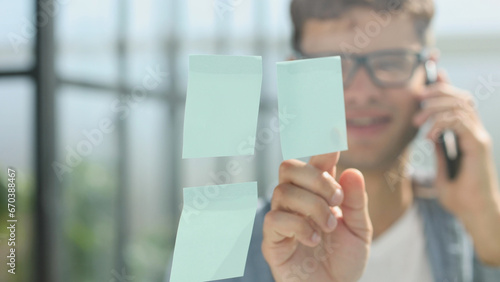 business man standing in front of stickers glass wall and write task on sticker at his office place