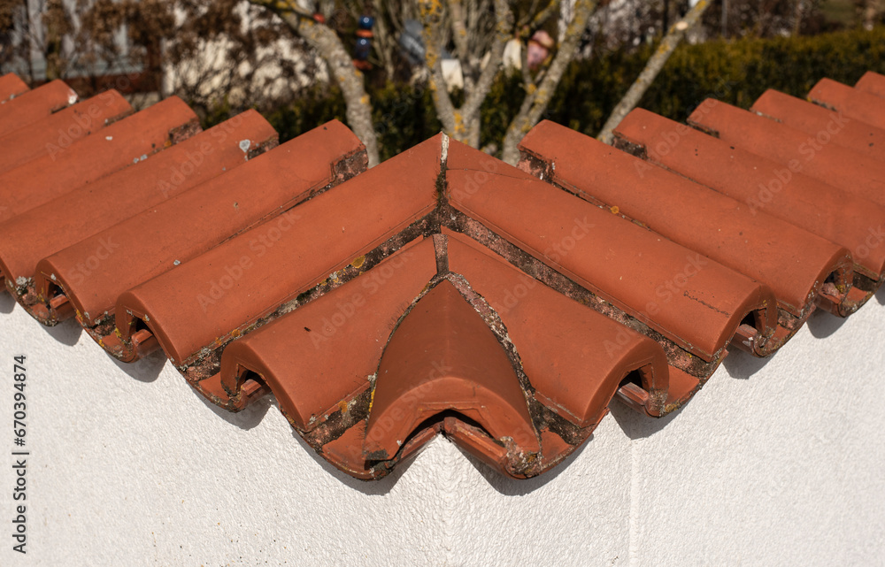 the corner of a plastered garden wall covered with red terracotta tiles