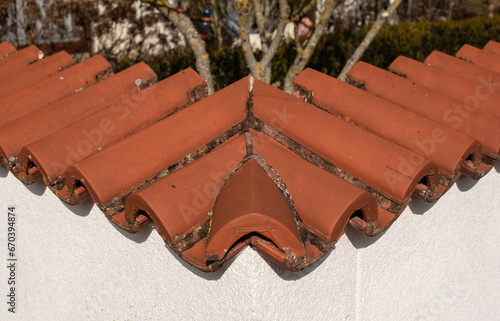 the corner of a plastered garden wall covered with red terracotta tiles