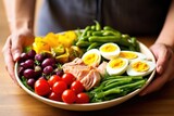 a hand topping nicoise salad with fresh green beans