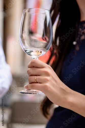 Left hand of a woman with a wedding ring, holding a glass of wine