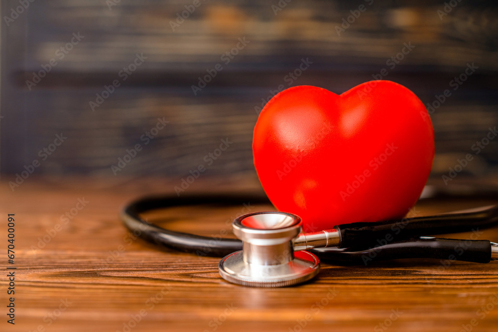 Red heart with stethoscope on brown background
