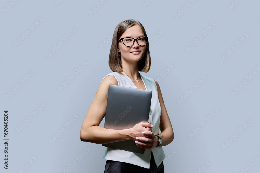 Young confident woman with laptop computer in hands on gray background Young confident woman with laptop computer in hands on gray background