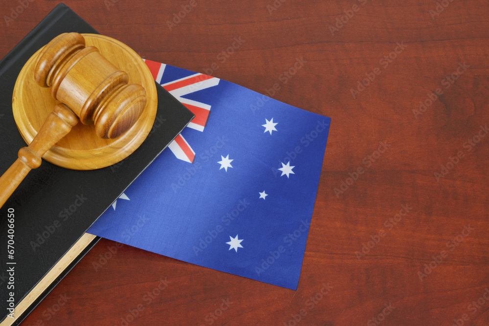 Judge gavel and legal book on wooden table with flag of Australia. Australian laws concept.