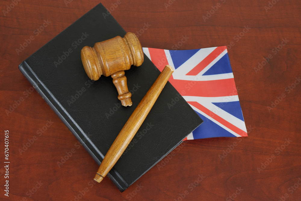 Broken gavel and legal book with British flag on wooden table. Problems in legal system of UK.