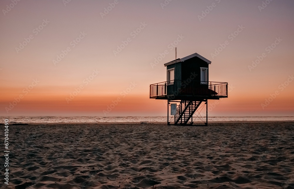 Serene beach scene featuring a wooden hut nestled in the sand at sunset in Langeoog, North Sea.