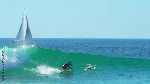 Cinematic pan follow France goofy rider surfing right by sailboat right male surfer huge wave swell morning daytime Hossegor Seignosse Biarritz Spain sunny daylight WSL Quiksilver Roxy Pro in wetsuit photo
