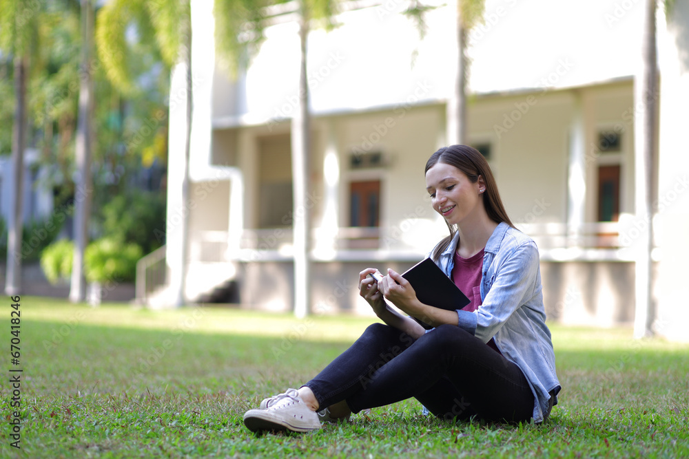 A girl sitting on the campus lawn reading a book. A girl sitting on the campus lawn reading a book.