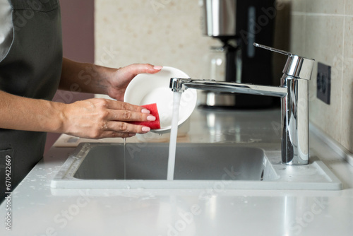 Close-up of a woman washing dishes in the kitchen. 
