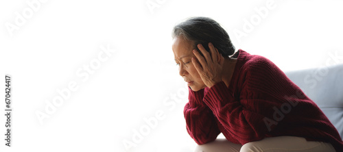 Senior woman sitting on the sofa at home is sick and has a headache.