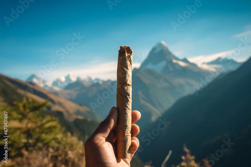 Hand holding a smoking joint in the himalaya, weed, mountains, himalaya mountains in the bacckground