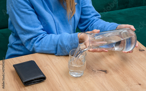 Dziewczyna nalewa wodę do szklanki 
