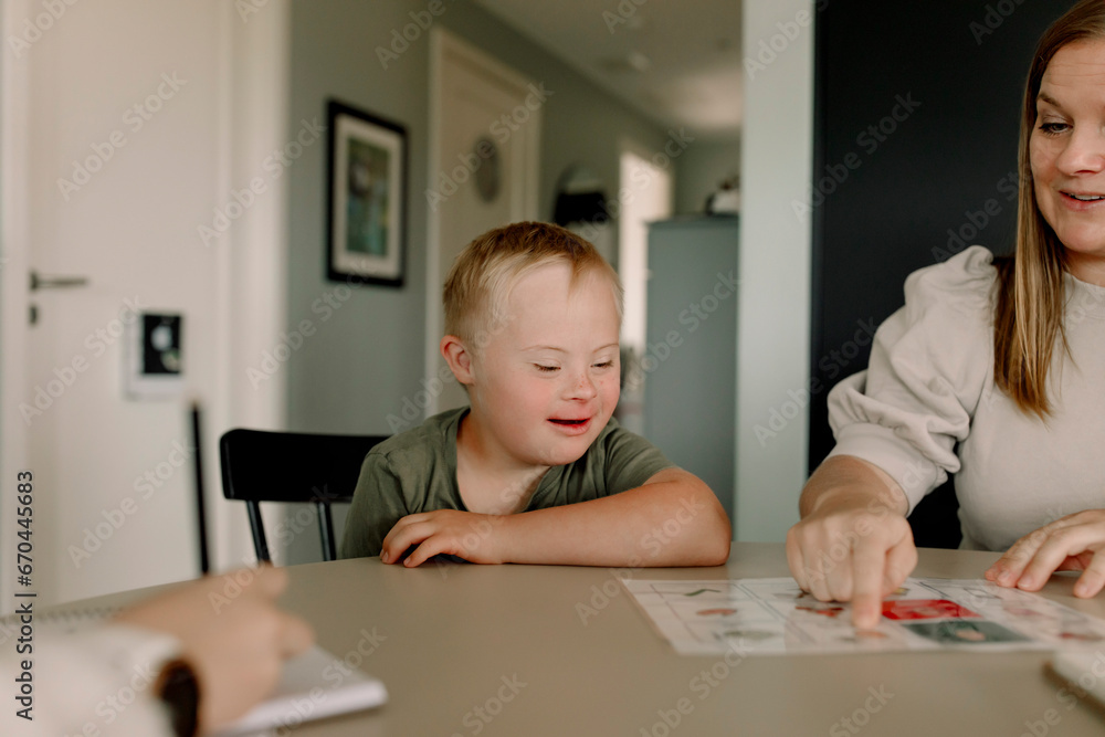 Mother teaching boy with down syndrome at home Mother teaching boy with down syndrome at home