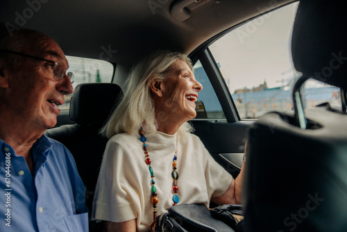 Cheerful senior couple enjoying taxi ride in city